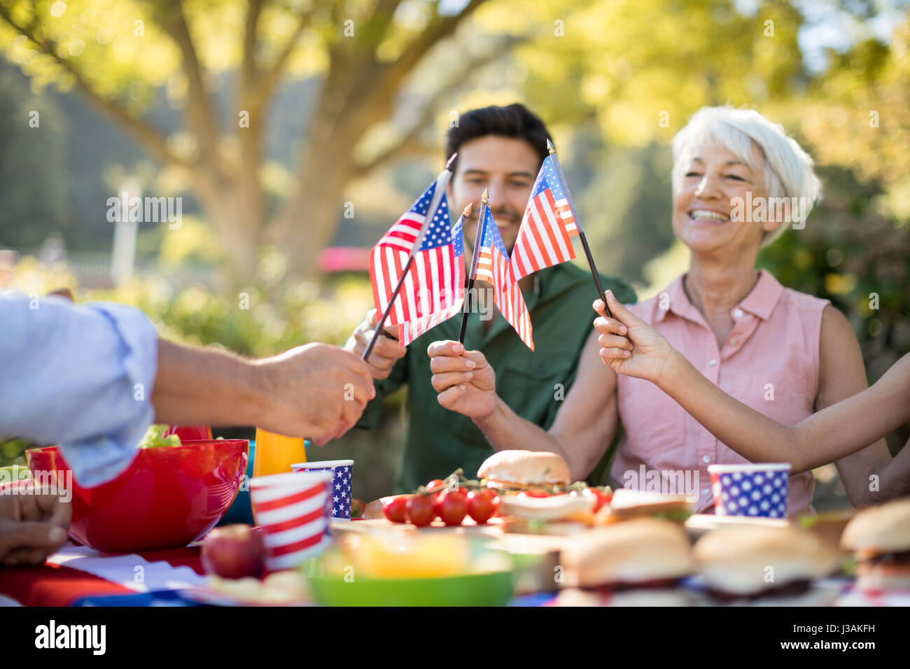 Glückliche Familie halten amerikanische Flaggen und mit Essen im park Stockfoto