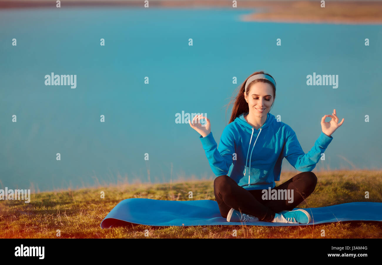 Glückliches Mädchen auf Yoga-Matte in der Natur meditieren Stockfoto