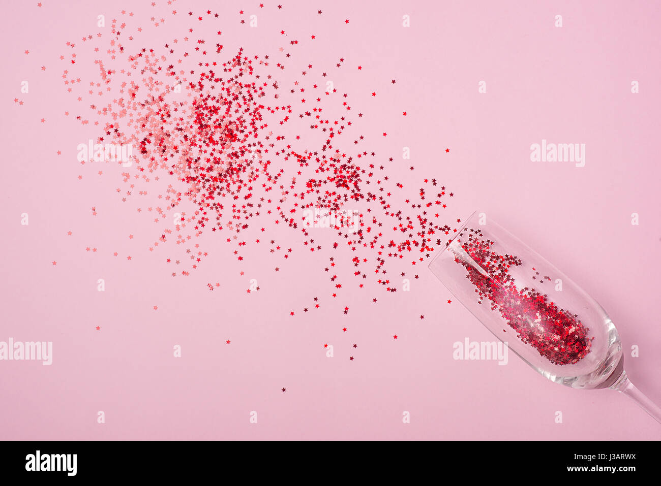 Wohnung lag der Feier. Sektglas mit bunten Partystromer auf rosa Hintergrund. Stockfoto