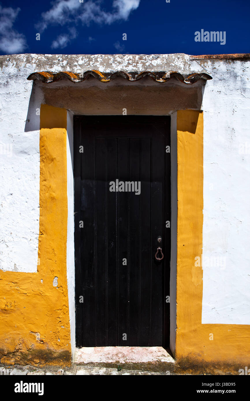 "Schwarze Tür, weiß getünchten Wänden und Fliesen": auf einer Straße in der alten Stadt Obidos Stockfoto