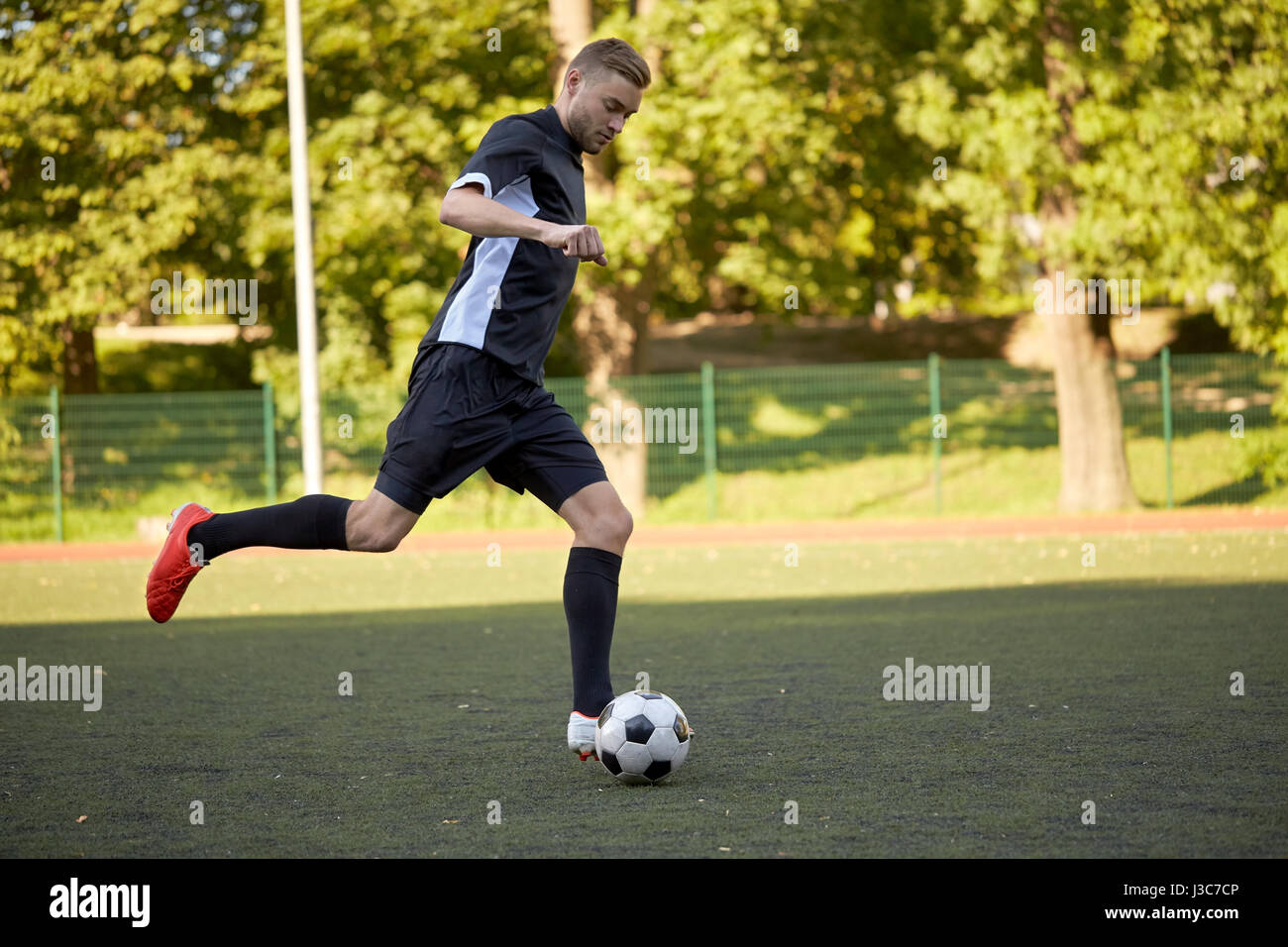 Fußballspieler mit Ball auf Fußballplatz spielen Stockfoto