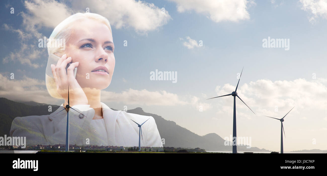 Geschäftsfrau mit Smartphone über Windkraftanlagen Stockfoto