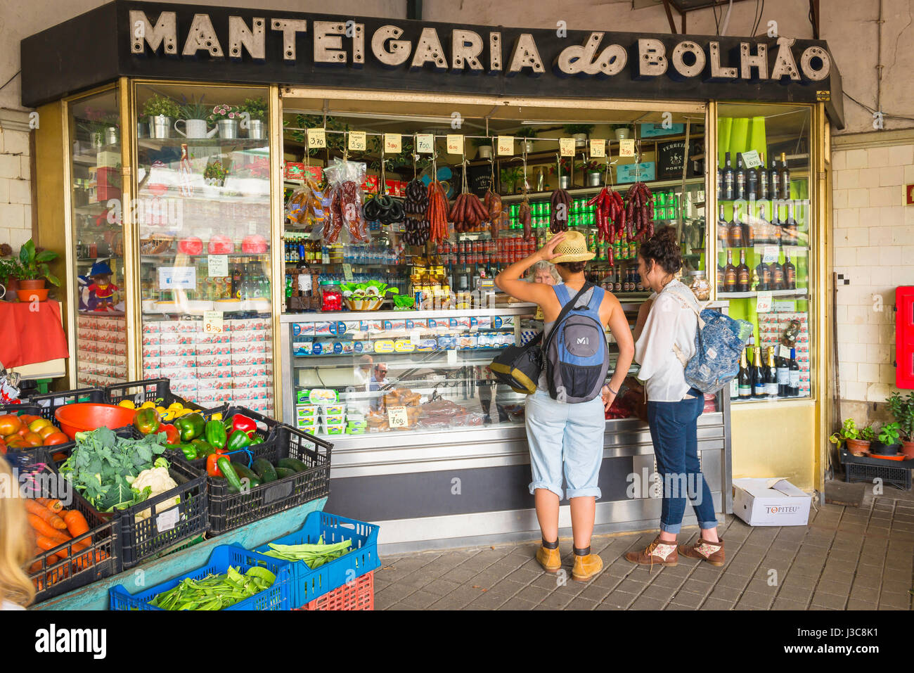 Markt für junge Frauen, Blick auf zwei junge Frauen, die Softdrinks von einem Händler im historischen Mercado do Bolhao im Zentrum von Porto, Portugal, kaufen. Stockfoto