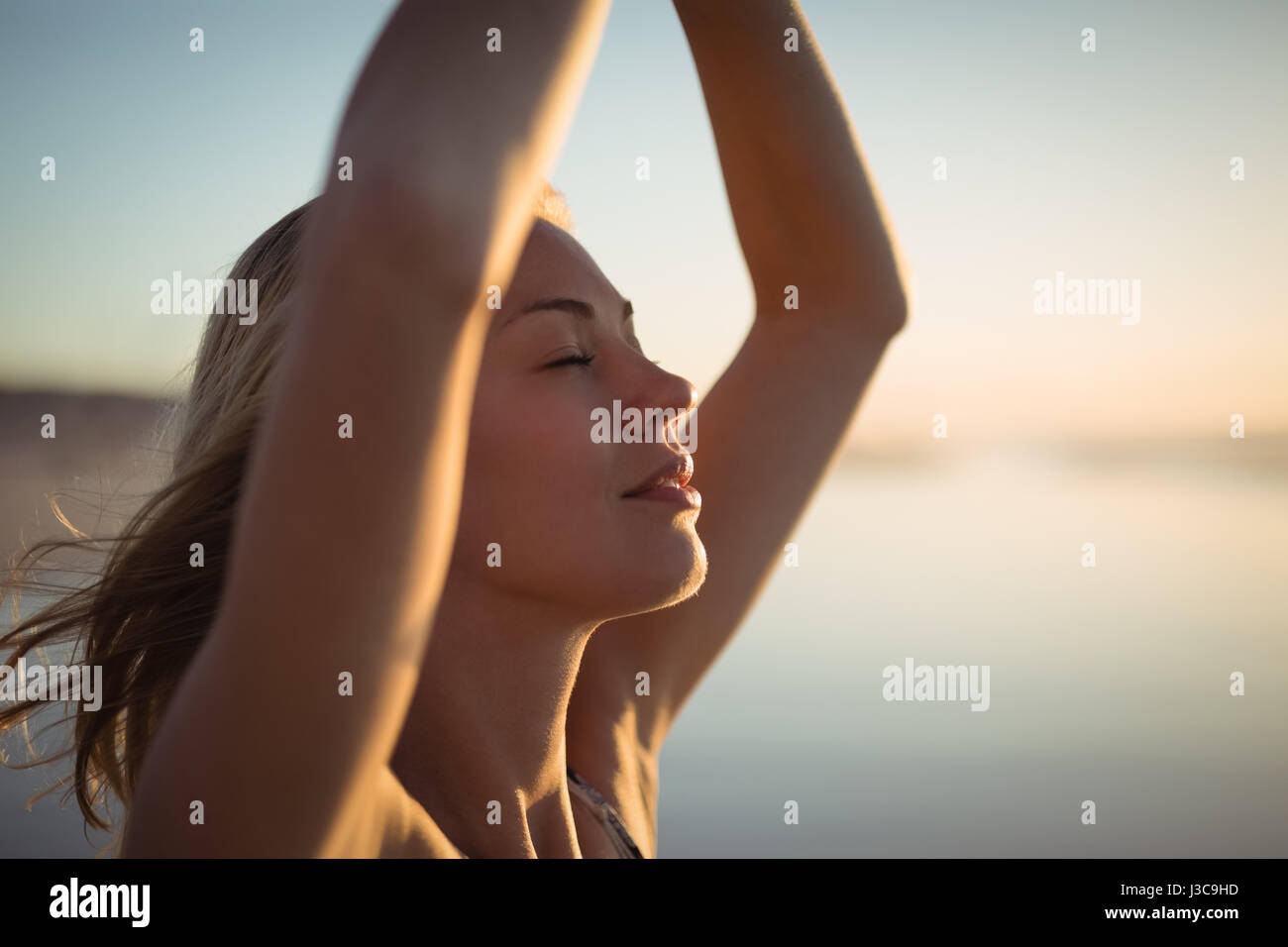 Junge Frau tut Yoga am Strand während der Dämmerung hautnah Stockfoto