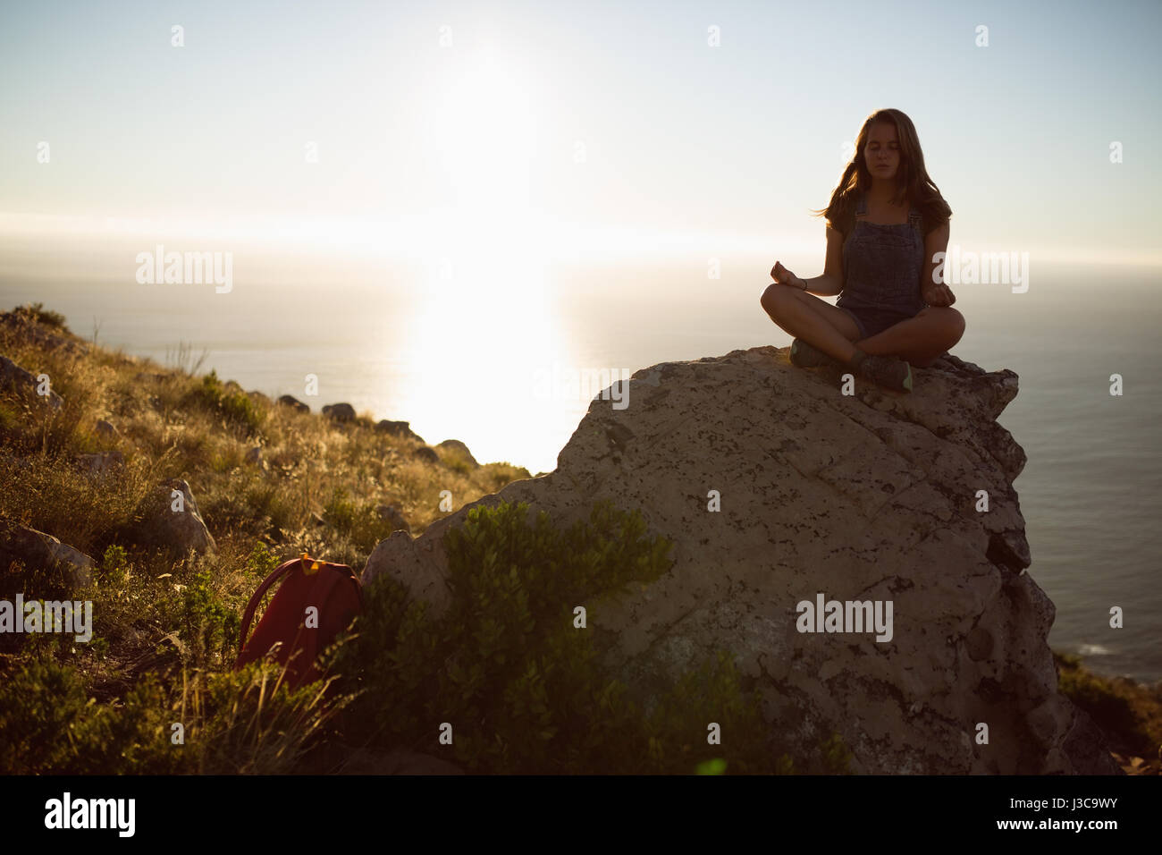 Frau, die Durchführung von Yoga auf einem Felsen in der Landschaft Stockfoto