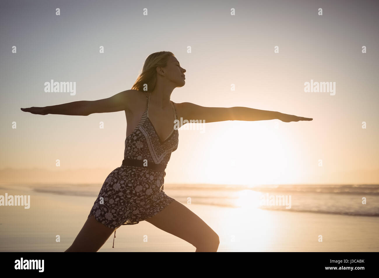 Junge Frau praktizieren Yoga am Strand während der Dämmerung Stockfoto