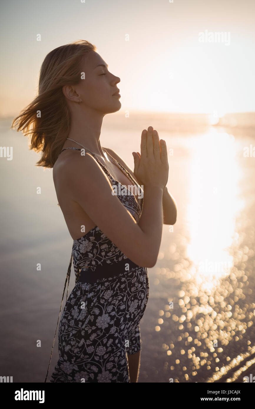 Seitenansicht der Frau tut Yoga am Strand während der Dämmerung Stockfoto