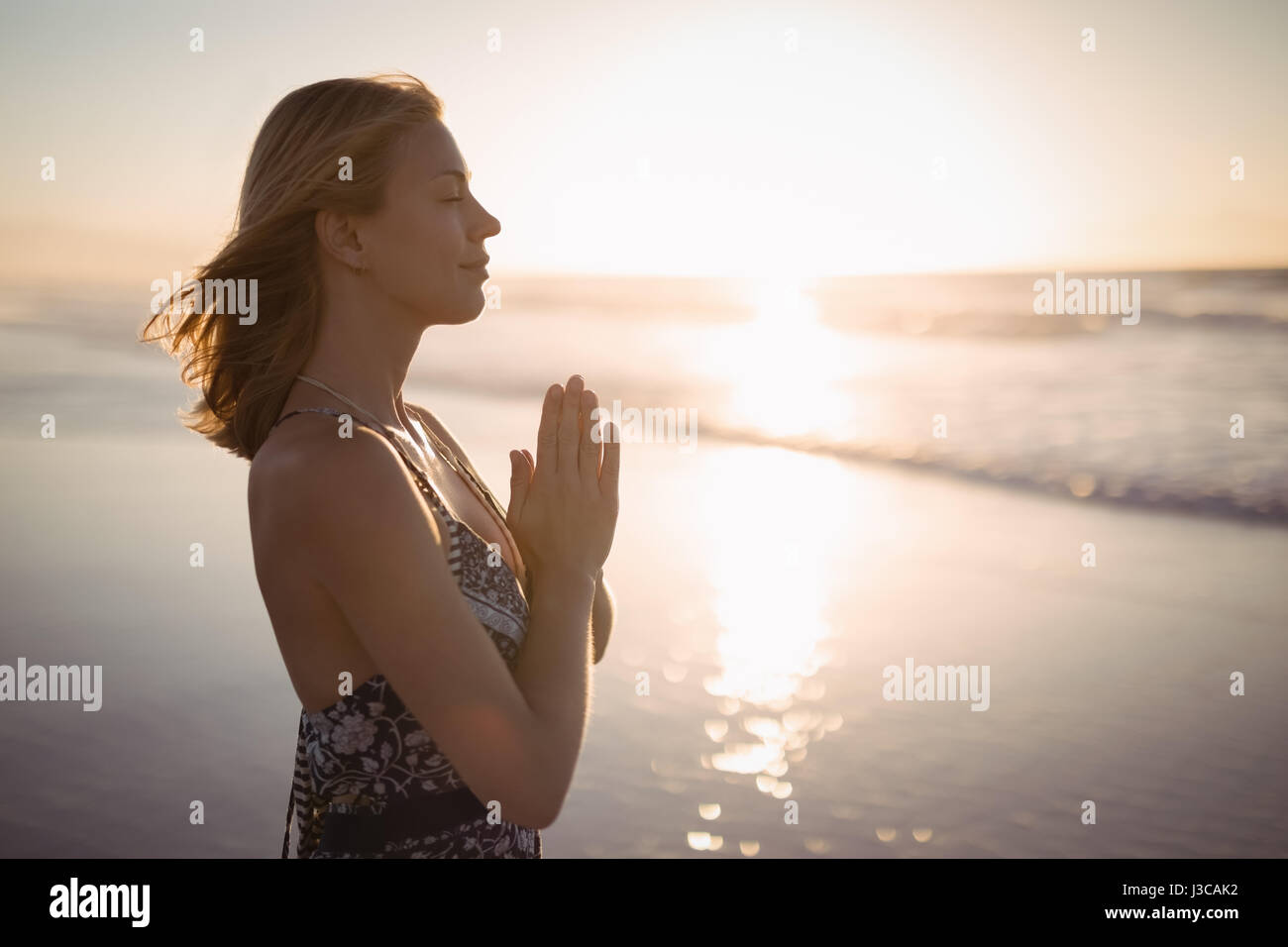 Seitenansicht der jungen Frau tun Yoga am Strand während der Dämmerung Stockfoto