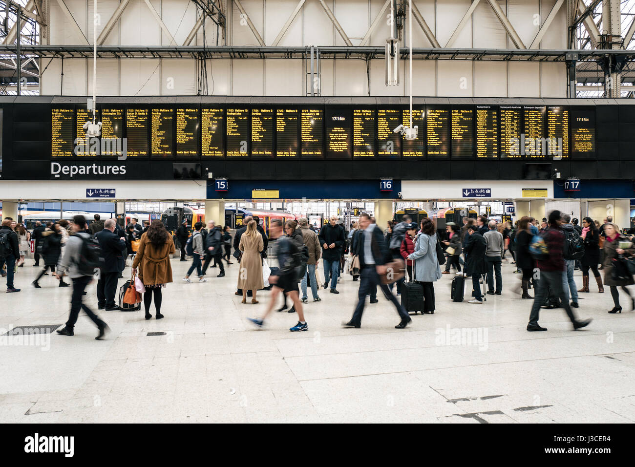 Pendler gehen vorbei an der Abfahrtstafel im Zentrum von London Waterloo Station. Stockfoto