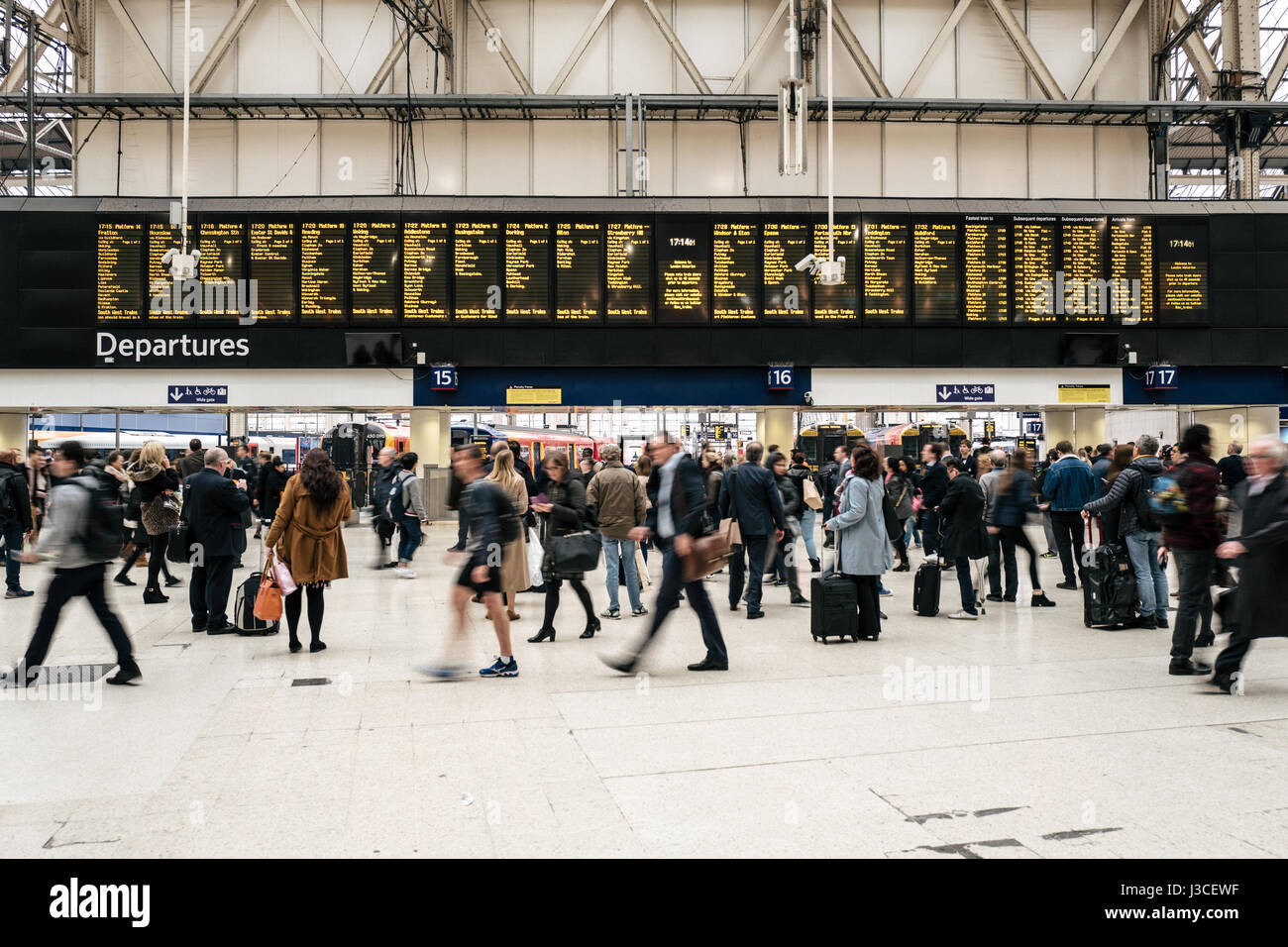 Pendler gehen vorbei an der Abfahrtstafel im Zentrum von London Waterloo Station. Stockfoto