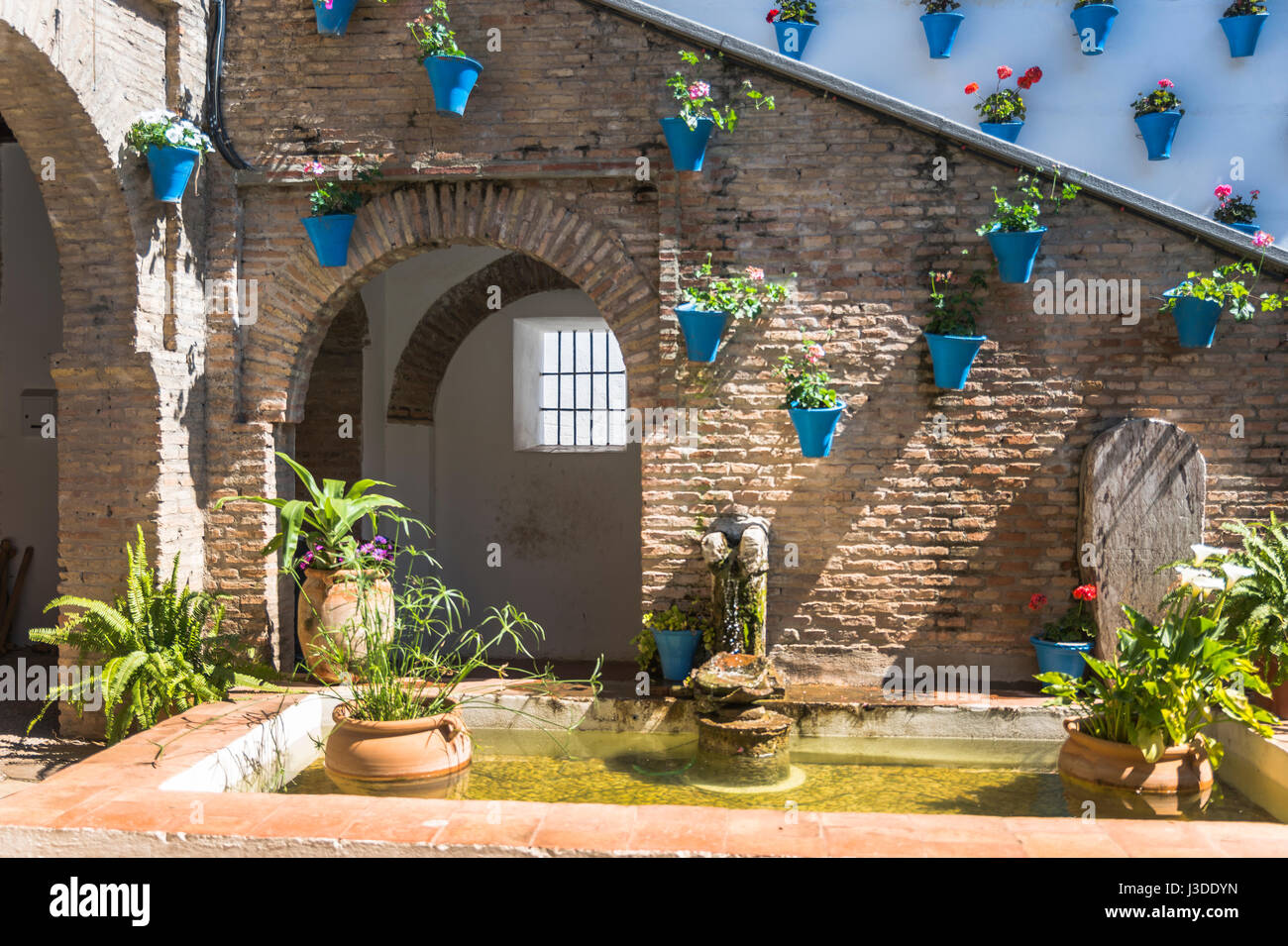 Terrasse mit blauen Töpfe mit Blumen und Grünpflanzen mit Wasser Fontain in kleinen Teich in Spanien Stockfoto