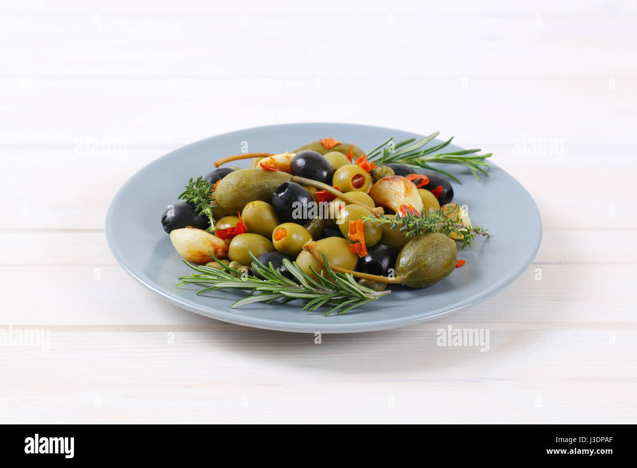 Teller mit grünen und schwarzen Oliven mit Knoblauch, Kapern und Kapern Beeren Stockfoto