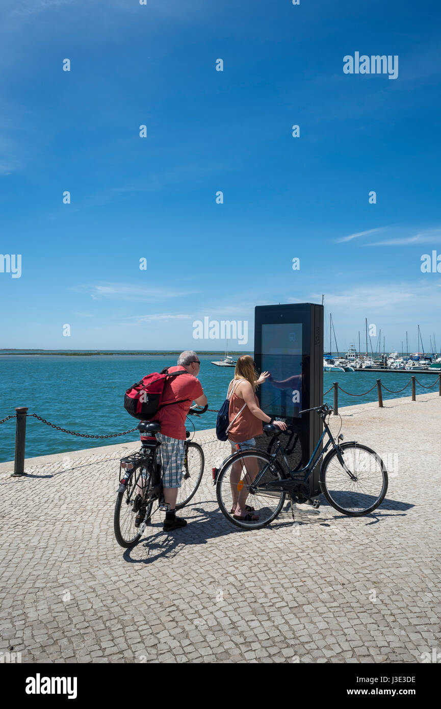 paar Touristen auf Fahrrädern mit einem interaktiven Touristenkarte in Olhao, Algarve, Portugal Stockfoto