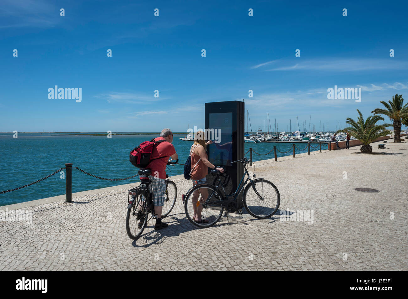 paar Touristen auf Fahrrädern mit einem interaktiven Touristenkarte in Olhao, Algarve, Portugal Stockfoto