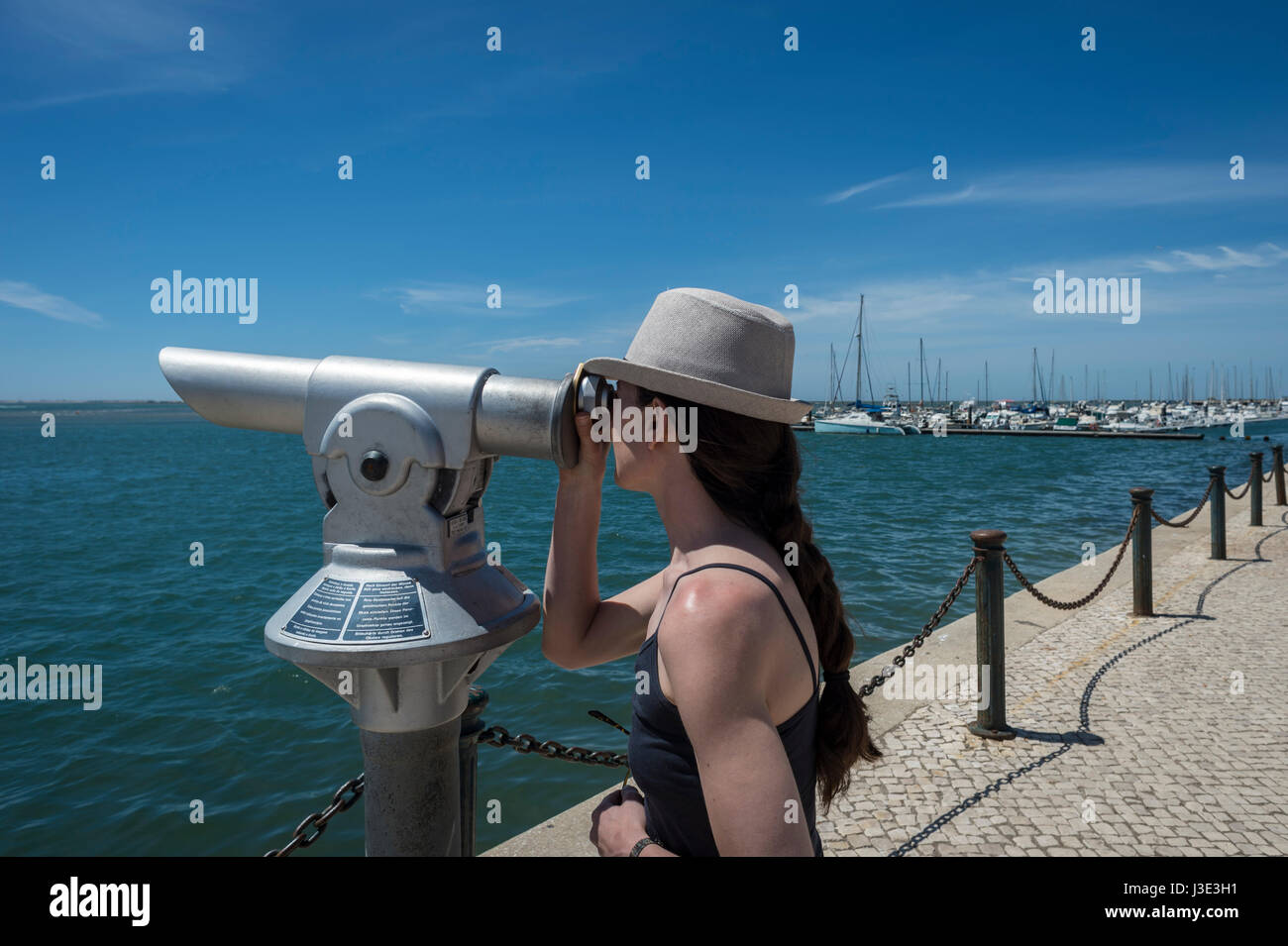 Frau, die durch eine Münze betrieben Teleskop direkt am Meer Stockfoto