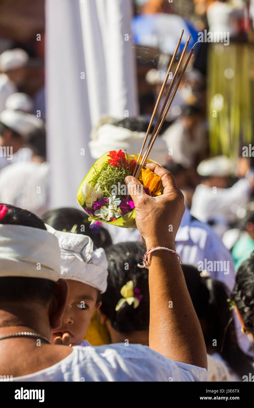 Räucherstäbchen und religiöse Angebote der Canang Sari in die ausgestreckte Hand von einem Hindu Mann während einer religiösen Zeremonie auf Bali in einem Hindu-Tempel Stockfoto
