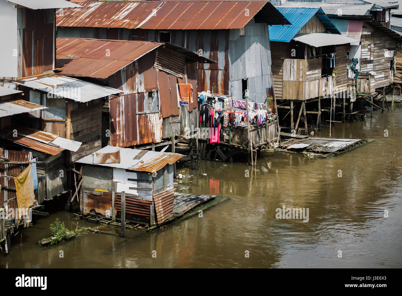 Grundlegende einfache Behausungen in Form von hölzernen Hütten oder Häusern, die den riverine Kalimantan am Flussufer in indonesischen Borneo Einwohner hat. Stockfoto