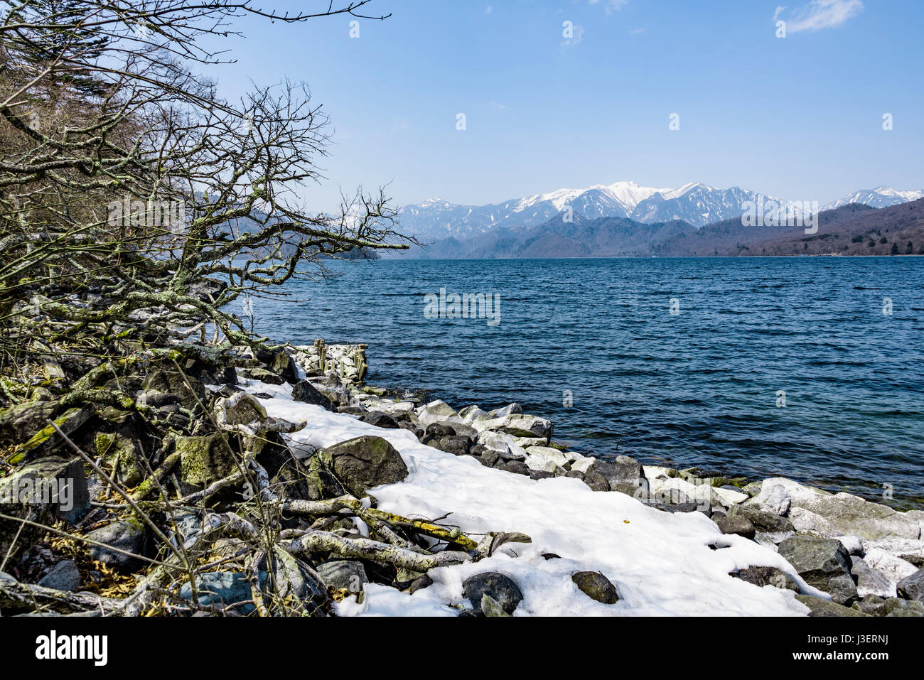 Der See Chuzenji, mit Schnee in den Bergen im Frühjahr mit einer Kappe bedeckt. Stockfoto