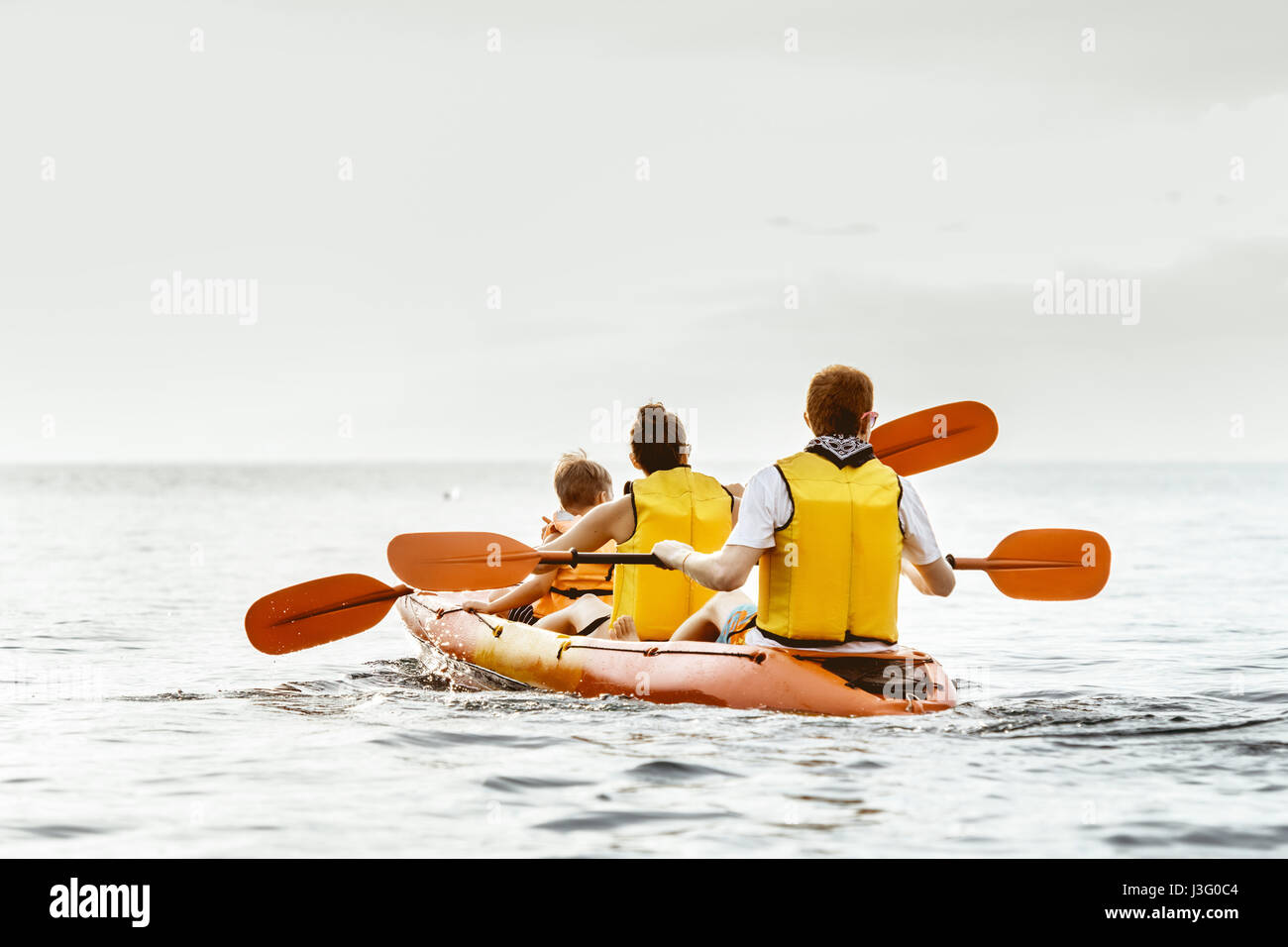 Familie mit drei Personen schwimmt mit dem Kajak auf dem ruhigen Meer Stockfoto