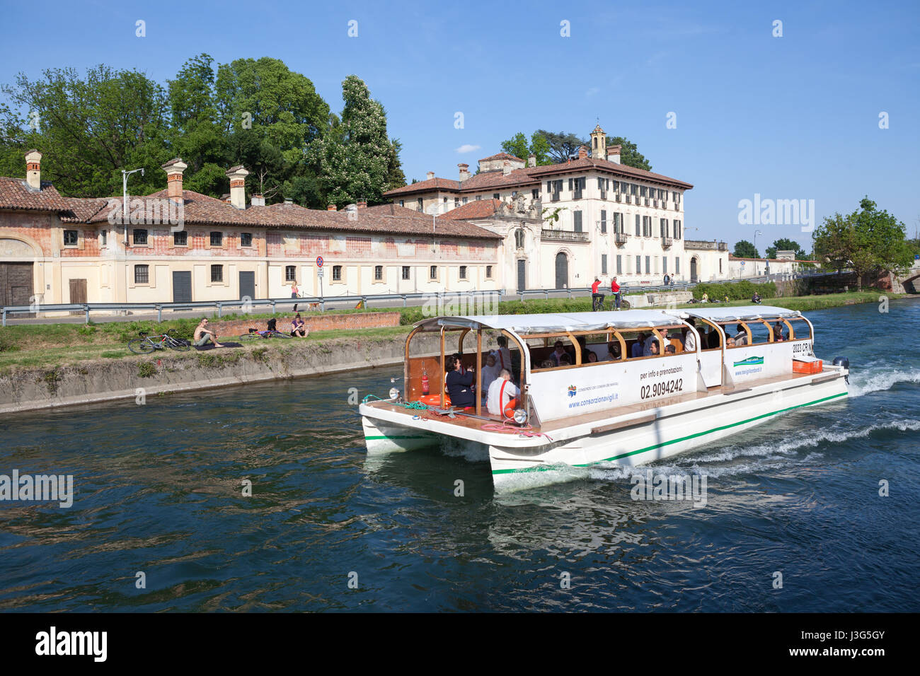 Ein Touristenboot Kreuzfahrt auf dem Naviglio Grande-Fluss, im Hintergrund Villa Visconti Castiglione Maineri, wenige Gehminuten von Mailand. Cassinetta di L Stockfoto