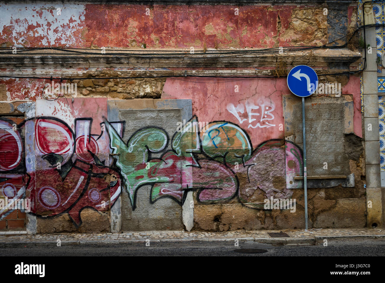 Linkskurve Straßenschild vor einem alten verlassenen Gebäude mit Graffiti bedeckt. Stockfoto
