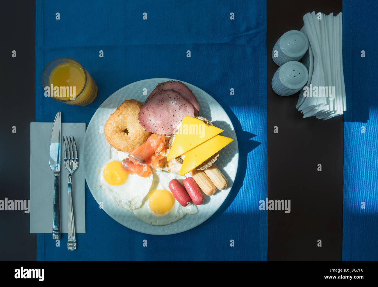 Leckeres Frühstück mit gebratenen Eiern, Wurst, Sandwichs und Orangensaft Stockfoto