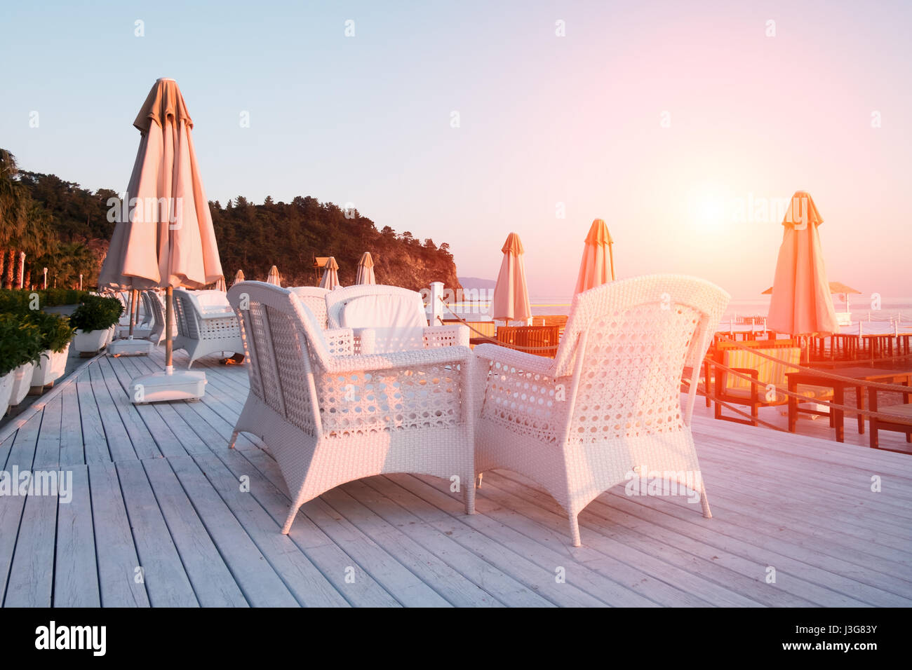 Sommer-Restaurant am Strand. Atemberaubenden Blick auf das Mittelmeer. Weiße Holzterrasse und geflochtene Möbel Stockfoto