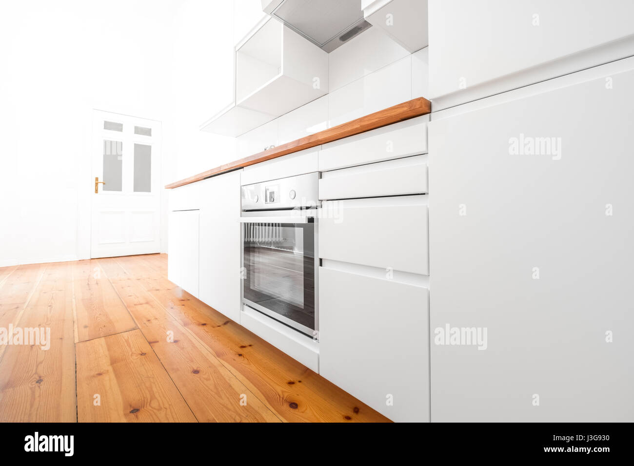 weiße Küche - moderne neue Küche mit Holzboden Stockfoto