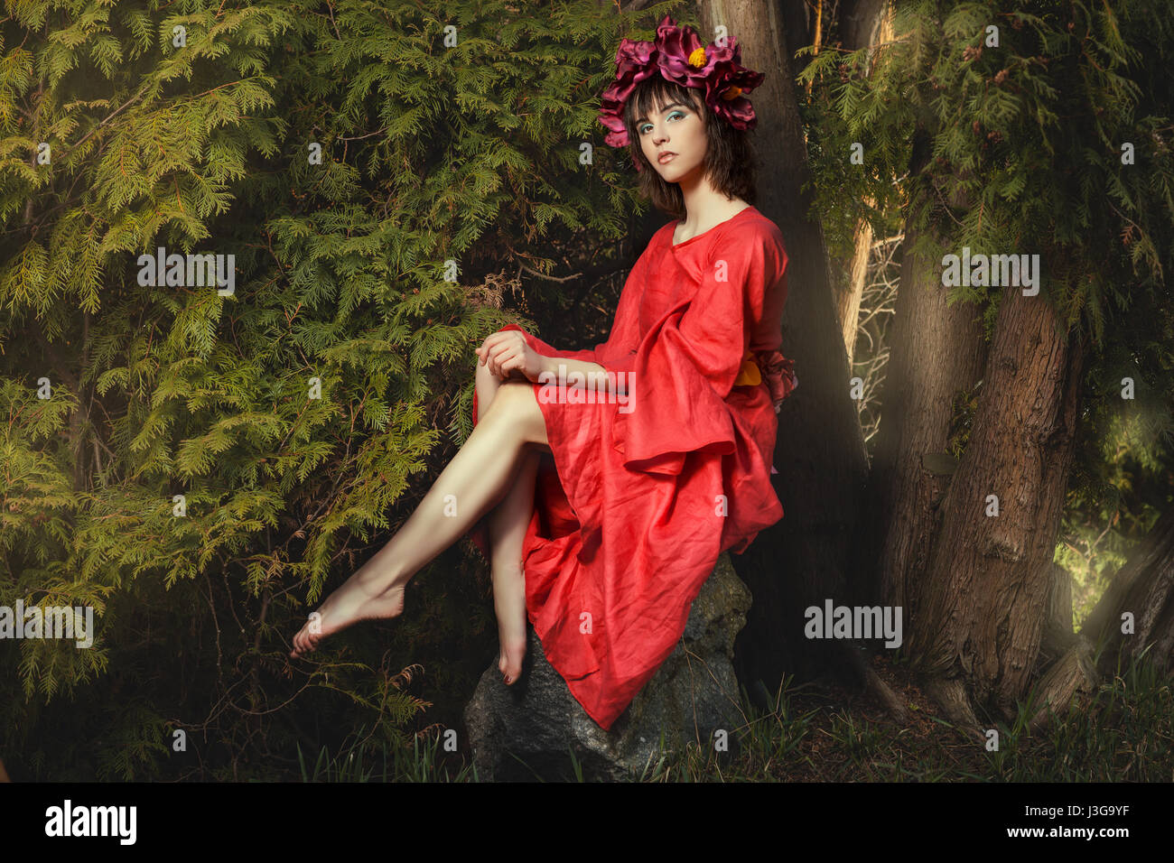 In der Waldfee auf ein Rock-Mädchen mit roten Kranz von Blumen auf dem Kopf sitzen. Stockfoto
