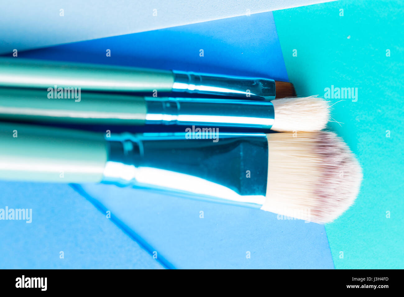 Ihr Leben in Shades of Blue: Stillleben mit einem Make-up-Pinsel platziert auf einem Multi-Ton-Schattierungen von blau. Stockfoto