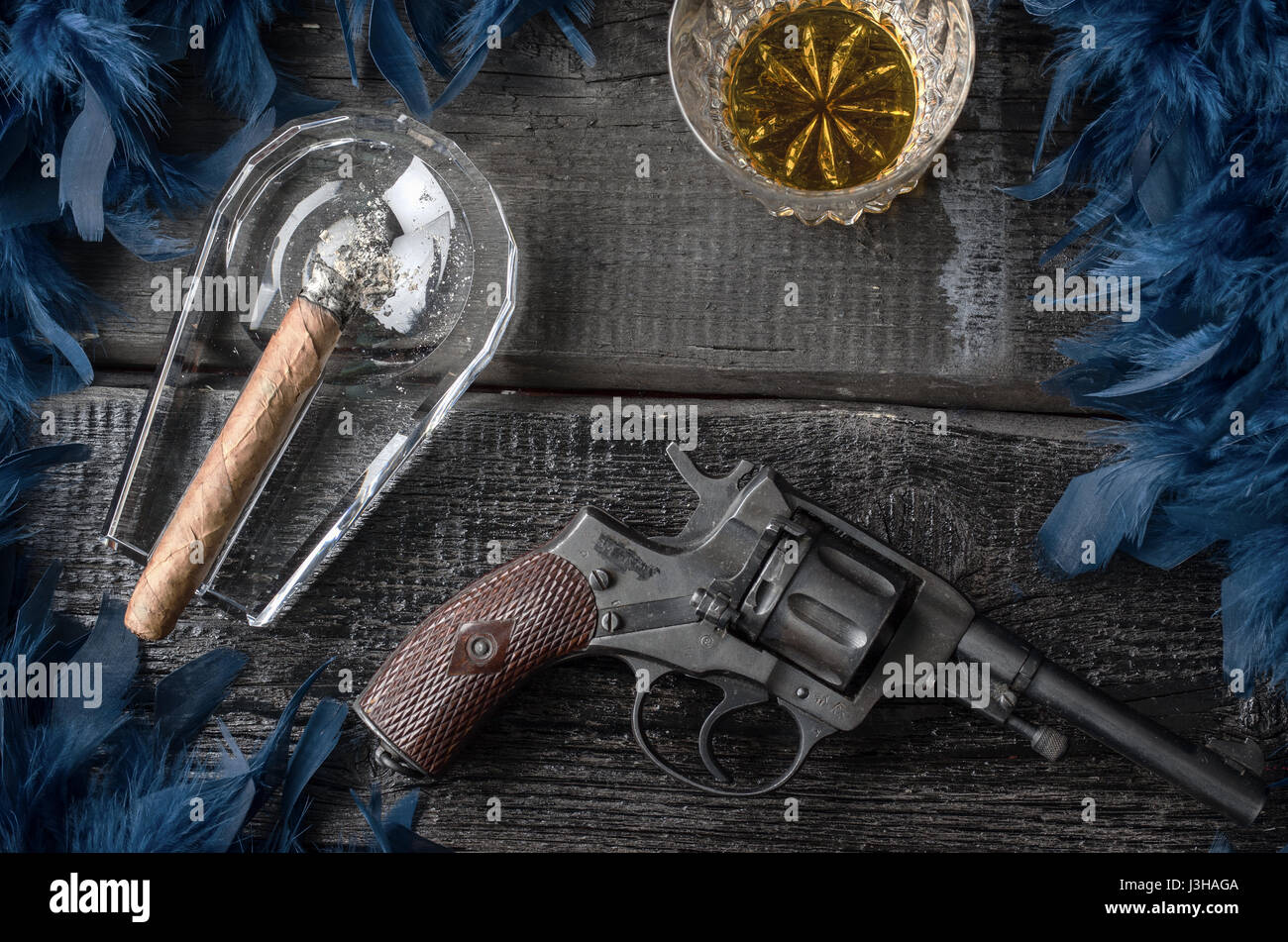 Thompson-Pistole, Revolver, Zigarren Aschenbecher, Whiskeyglas und blaue Federboa Stockfoto