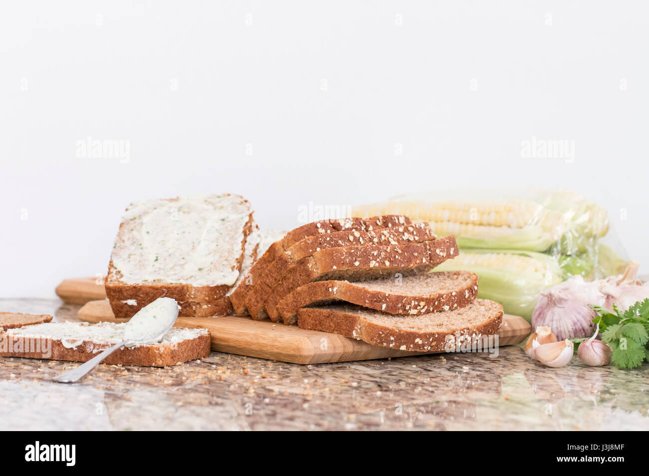 Bereiten Sie machen Knoblauch Brot auf Holzblock und Kräutern auf Marmortisch Stockfoto