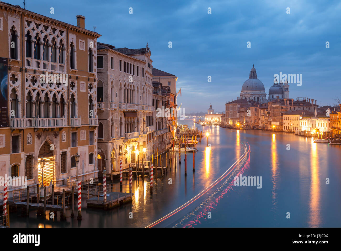 Dämmerung am Grand Canal in Venedig. Santa Maria della Salute Kirche taucht in der Ferne. Stockfoto