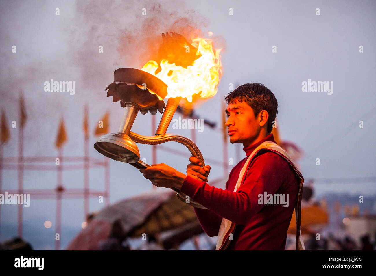 Ein Hindu Priester an den Ufern des Ganges / Fluss Ganges in Varanasi, Indien führt eine Zeremonie (Puja) mit einer Öllampe. Stockfoto