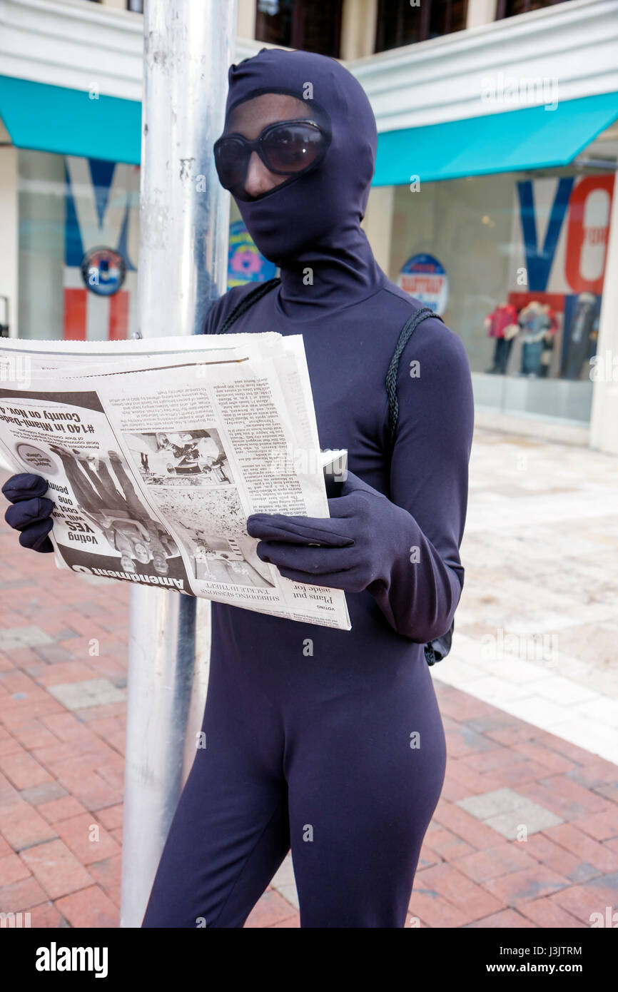 Miami Florida, Coconut Grove, Straßenkünstler, Bucking-Tipps, Pantomime, in Schwarz gekleidet, Lesen, Zeitung, Kostüm, Body, FL081026143 Stockfoto