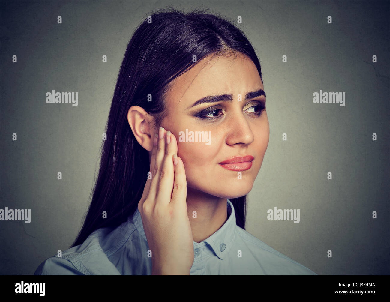 Tinnitus. Closeup Portrait krank weiblich mit Ohrenschmerzen berühren Kopf schmerzhaft auf graue Wand Hintergrund isoliert Stockfoto