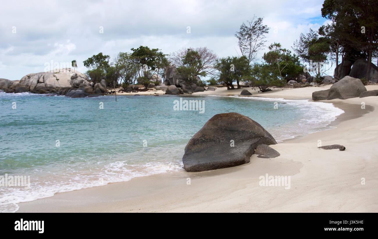 Natürliche Felsformation auf blau türkis farbigen Meer und weißen Sandstrand mit Pflanzen und Bäumen im Hintergrund in Belitung Island in der nach Stockfoto