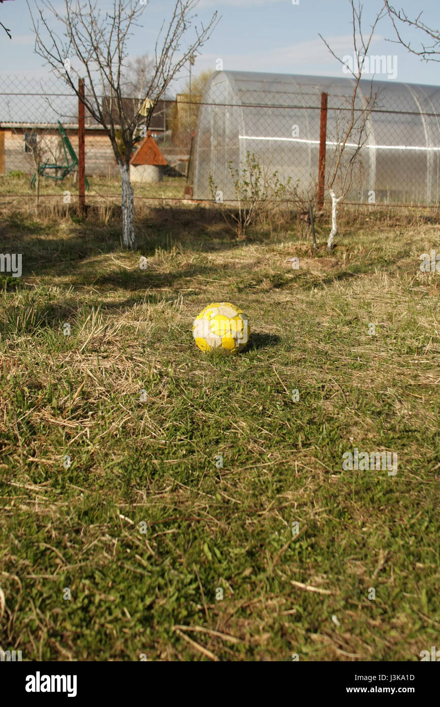 Leuchtend gelbe alte Fußball auf dem Rasen liegen und warten auf die Wirkung. Stockfoto