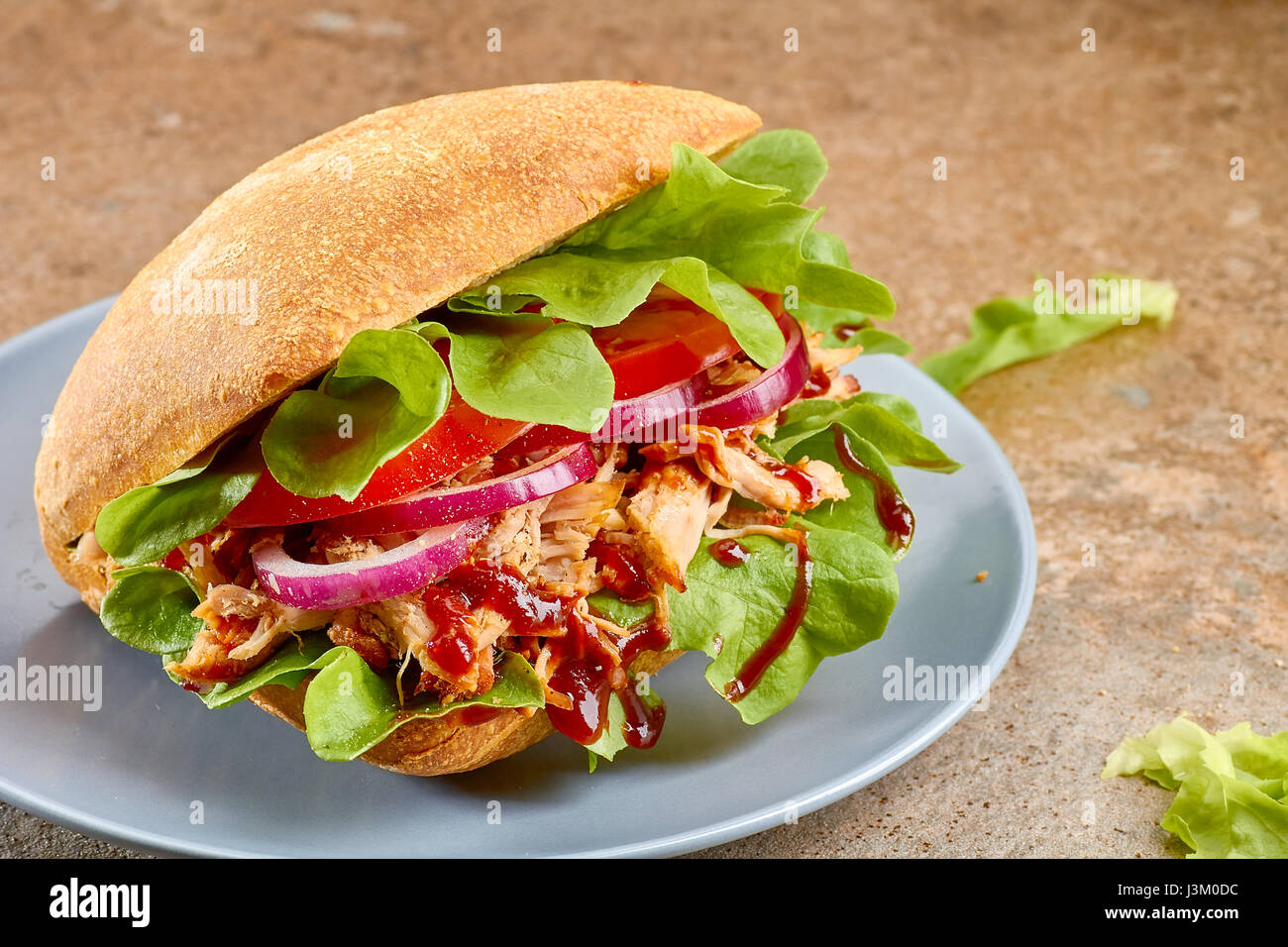 Sandwich mit zog Schweinefleisch, Tomaten und Salat auf blau Teller Stockfoto