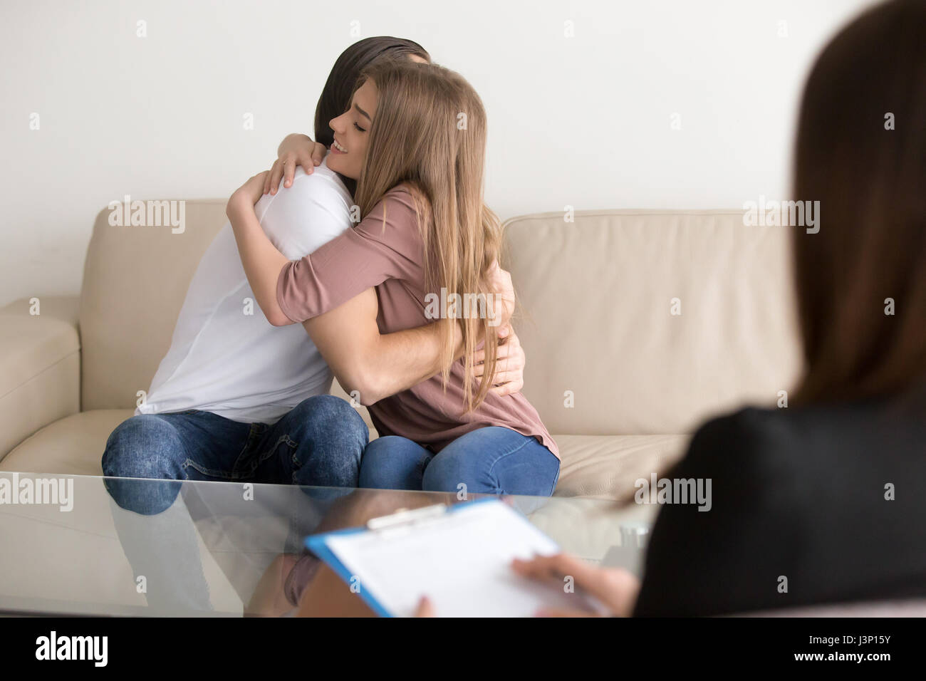 Junge Familie paar umarmt, auf Couch, Beratung weiblich Stockfoto