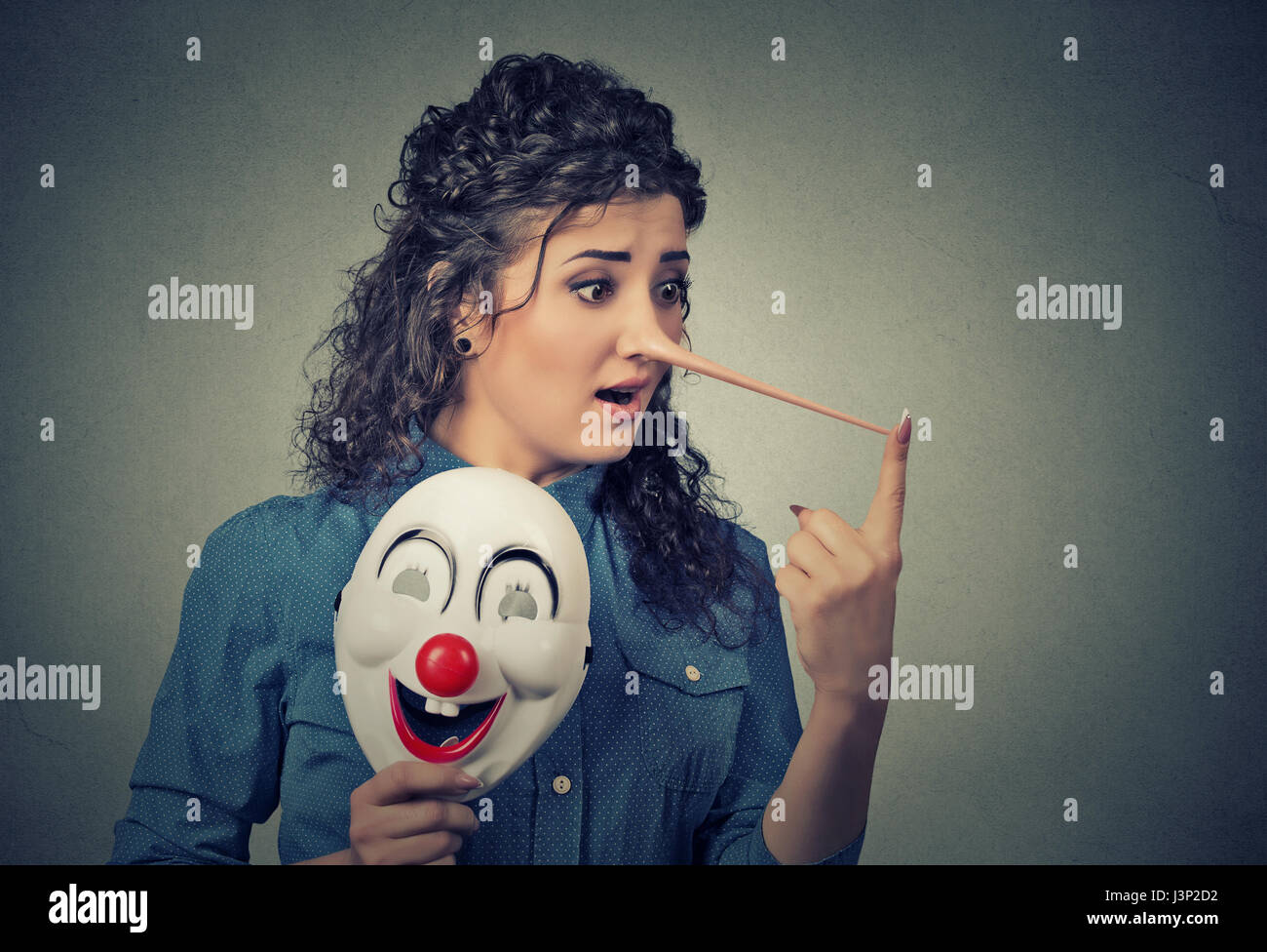 Frau mit langer Nase und Clown Maske auf graue Wand Hintergrund isoliert. Lügner-Konzept. Menschlichen Gesichtsausdruck, Emotionen, Gefühle. Stockfoto