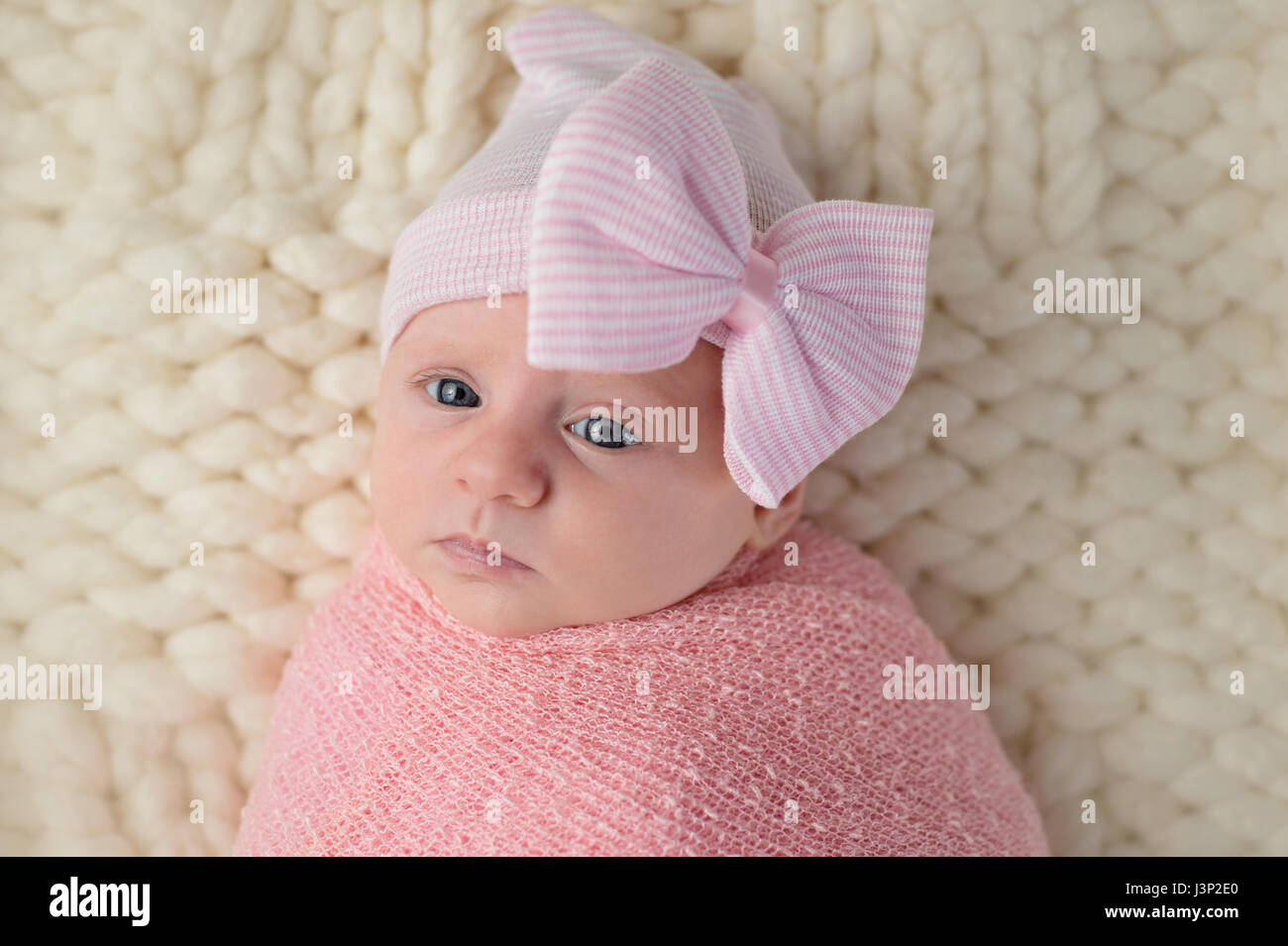 Studio-Porträt einer Warnung Monat alt, Neugeborenes Babymädchen. Sie trägt einen Hut mit einer großen Schleife und eingehüllt in ein rosa wickeln. Stockfoto