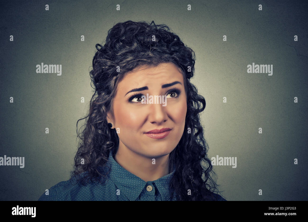 Porträt Closeup verwirrt skeptisch junge Frau auszudenken suchen auf graue Wand Hintergrund isoliert. Menschliche Ausdrucksformen, Emotionen, Gefühle, Körper lang Stockfoto