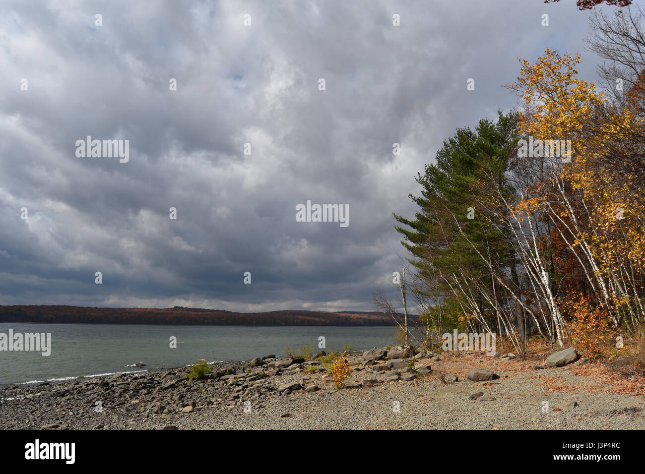 Leuchtende See mit stimmungsvoller Himmel und Bäume am Strand Stockfoto