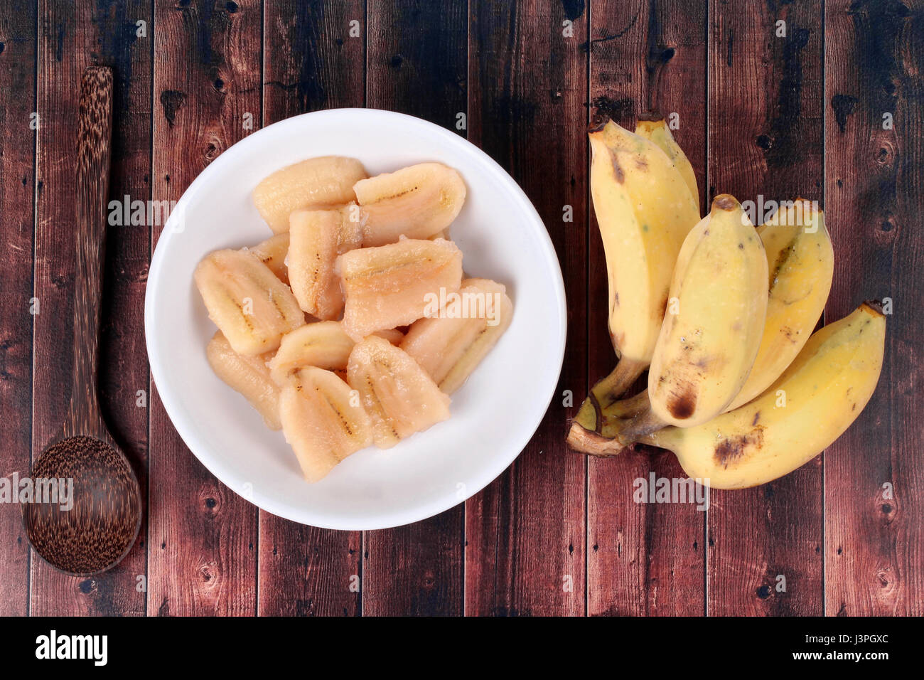 Thai beliebtes Dessert, fertig gekochte Banane in Sirup serviert und Löcher Banane serviert auf Holz. Stockfoto