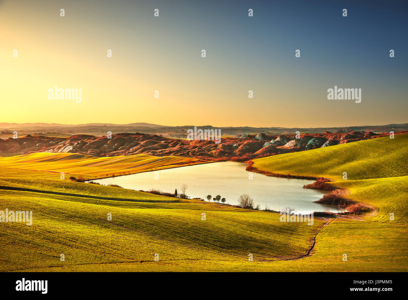 Toskana, Crete Senesi Landschaft in der Nähe von Siena, Italien, Europa. Kleiner See, grüne und gelbe Felder, blauer Himmel mit Wolken. Stockfoto