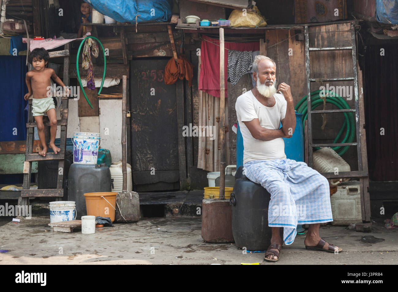 Älterer Mann sitzt vor seinem Haus, Mumbai, Indien Stockfoto