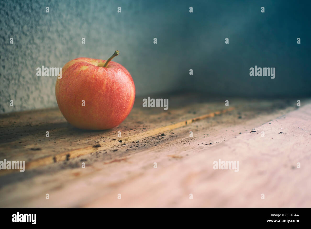 Ein roter Apfel auf einem alten Holztisch. Minimale Zusammensetzung. Stockfoto