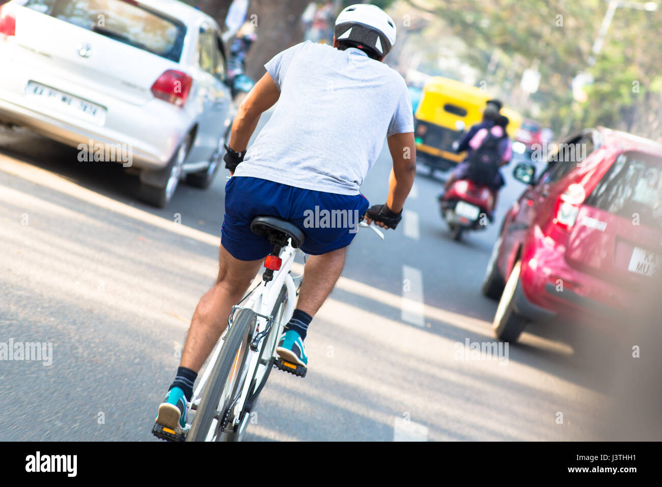 Ein Mann auf einem Fahrrad im dichten Verkehr in Bangalore, Indien Stockfoto