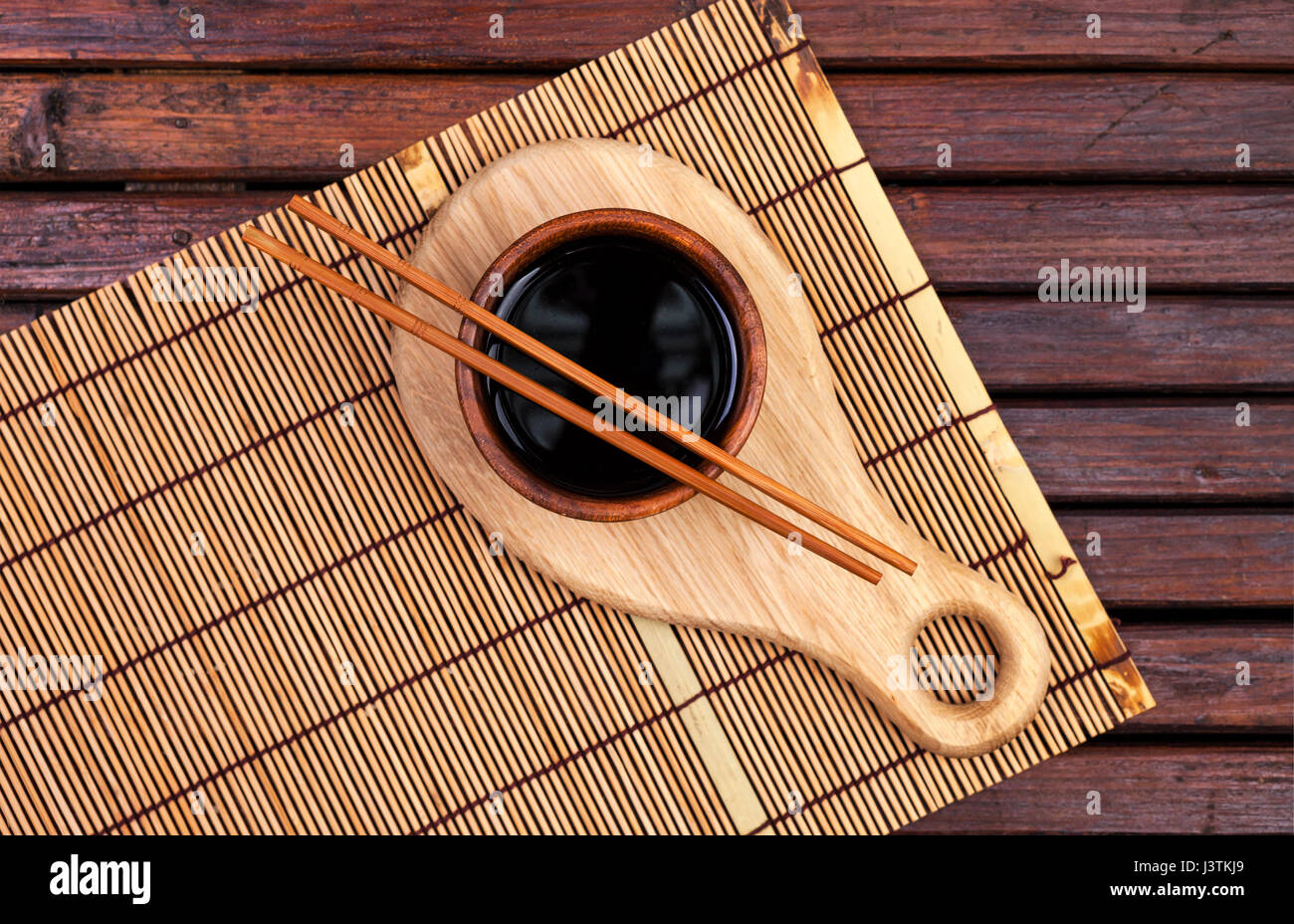Bambus Matte, Sojasauce, Stäbchen auf dunklen Holztisch. Draufsicht mit Textfreiraum Stockfoto